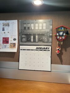 Calendar, opened to January page, shown hanging between flyer and tiny cuckoo clock.